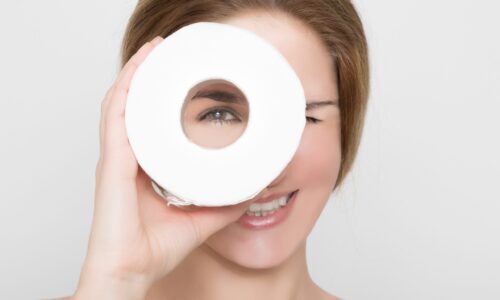 Beautiful woman looks through a roll of toilet paper
